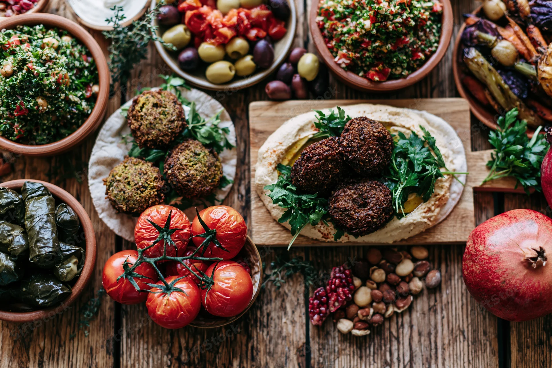 Middle eastern mezze spread with hummus, falafel, tabbouleh and olives on a rustic wooden table