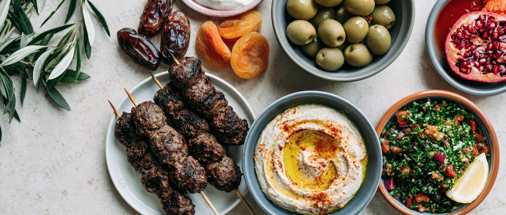 Middle eastern mezze spread with hummus, kebabs, olives and tabbouleh on a stone surface