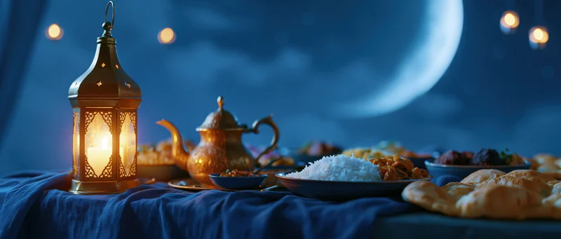 Iftar dinner spread with glowing lantern and traditional dishes on a blue cloth under a night sky with moon
