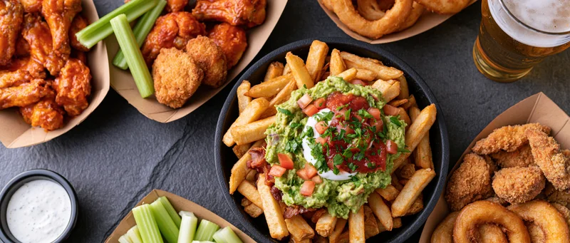 Overhead flat-lay of american bar food spread on dark slate surface