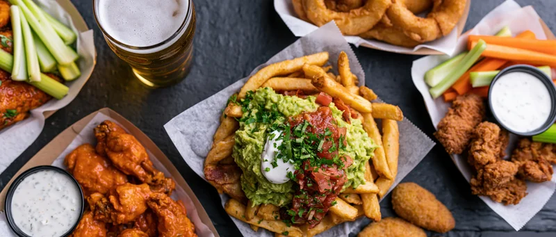 Overhead flat-lay of american bar food spread on dark slate surface