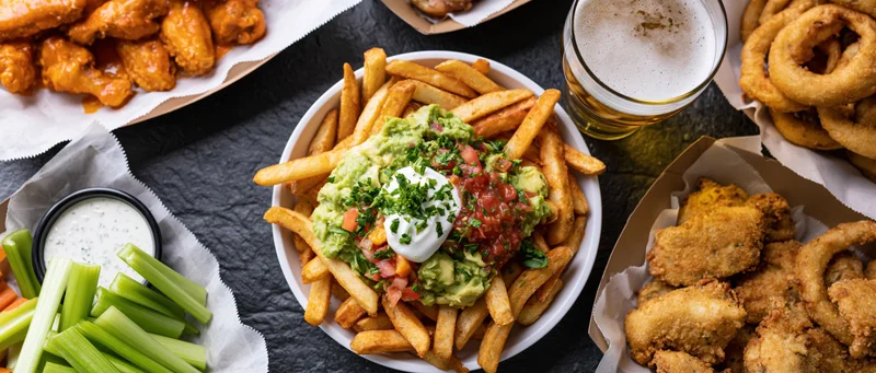 Overhead flat-lay of american bar food spread on dark slate surface