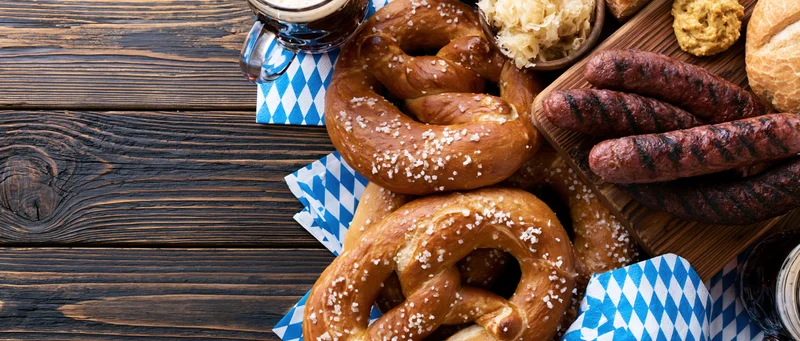 Pretzels and sausages with beer on a dark wooden table for oktoberfest celebration