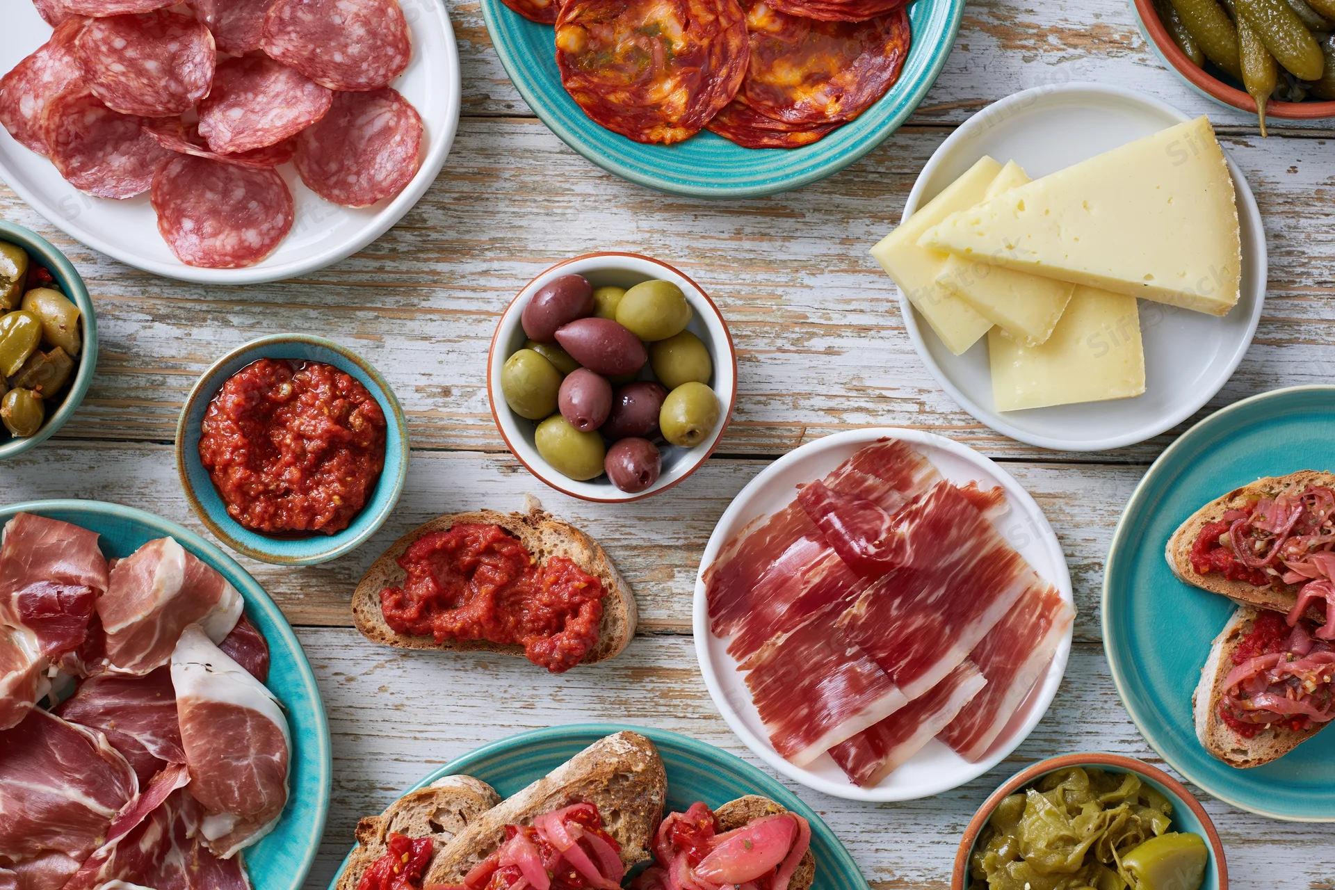 Spanish tapas spread with cured meats, cheese, olives and bread on a rustic wooden table
