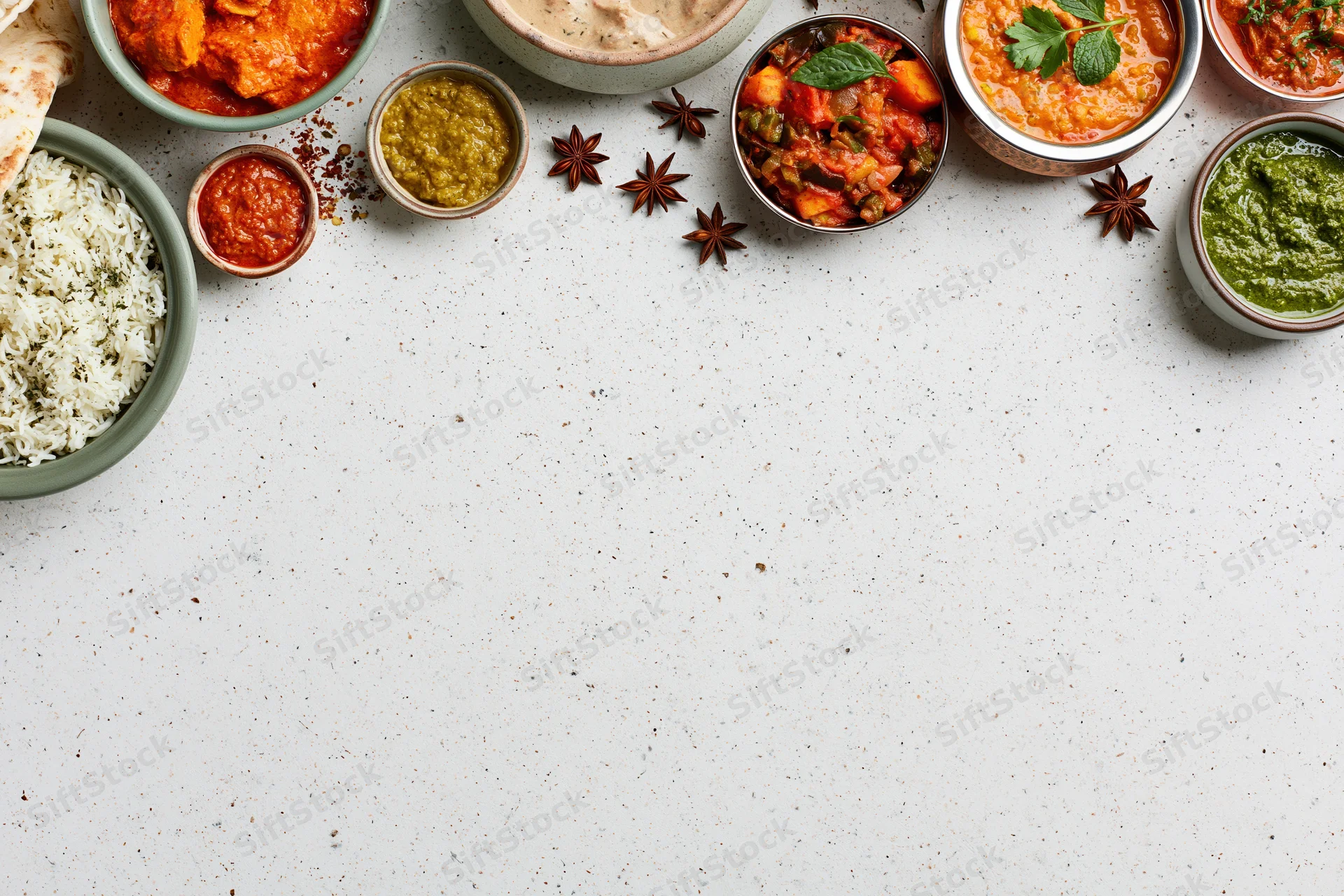 Assorted indian dishes arranged in a flat lay on a white surface with copyspace