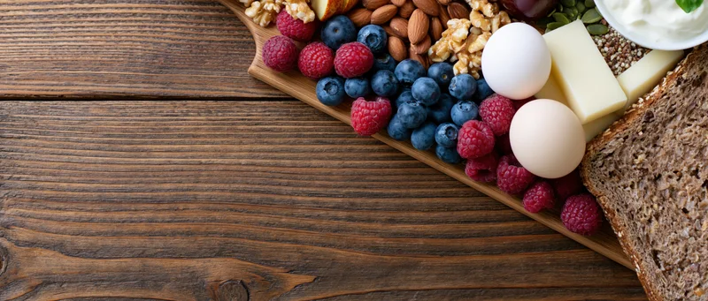Healthy breakfast ingredients arranged on wooden board with copyspace