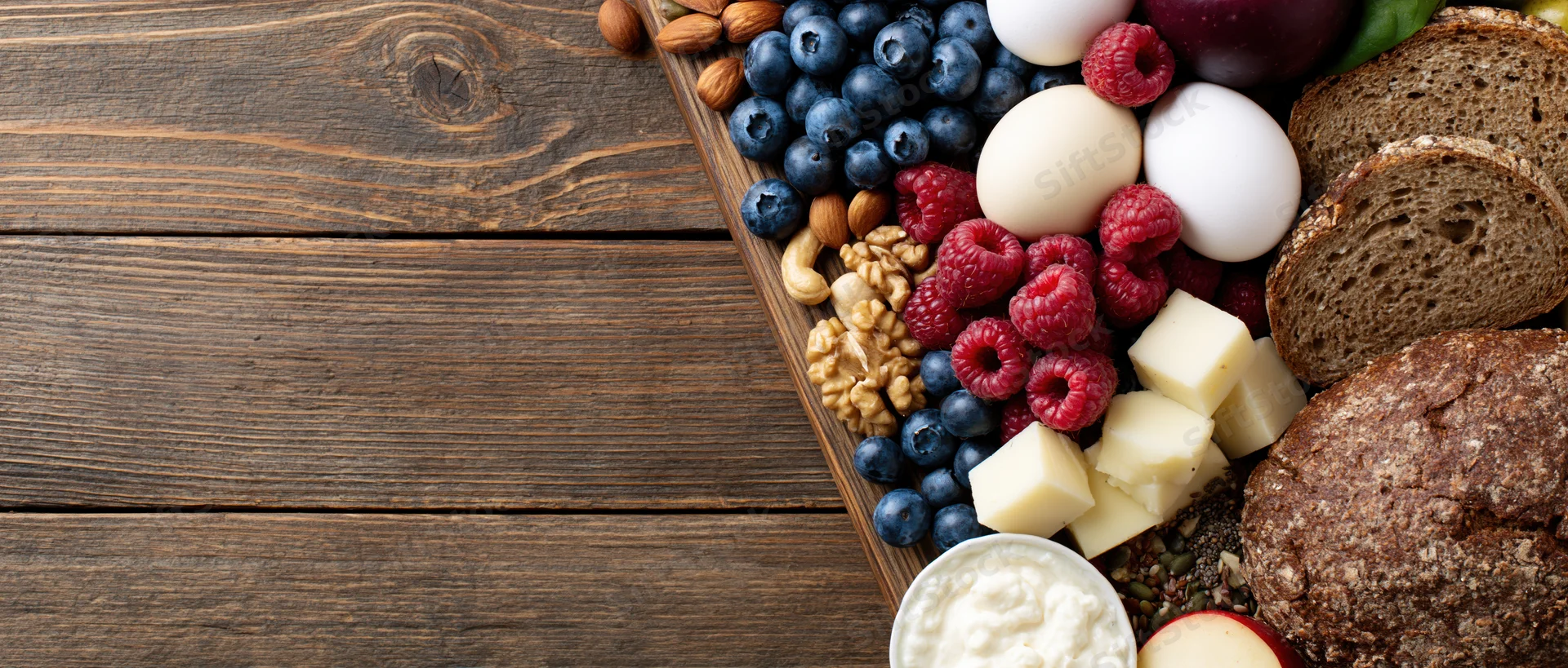 Healthy breakfast ingredients arranged on wooden board with copyspace on left