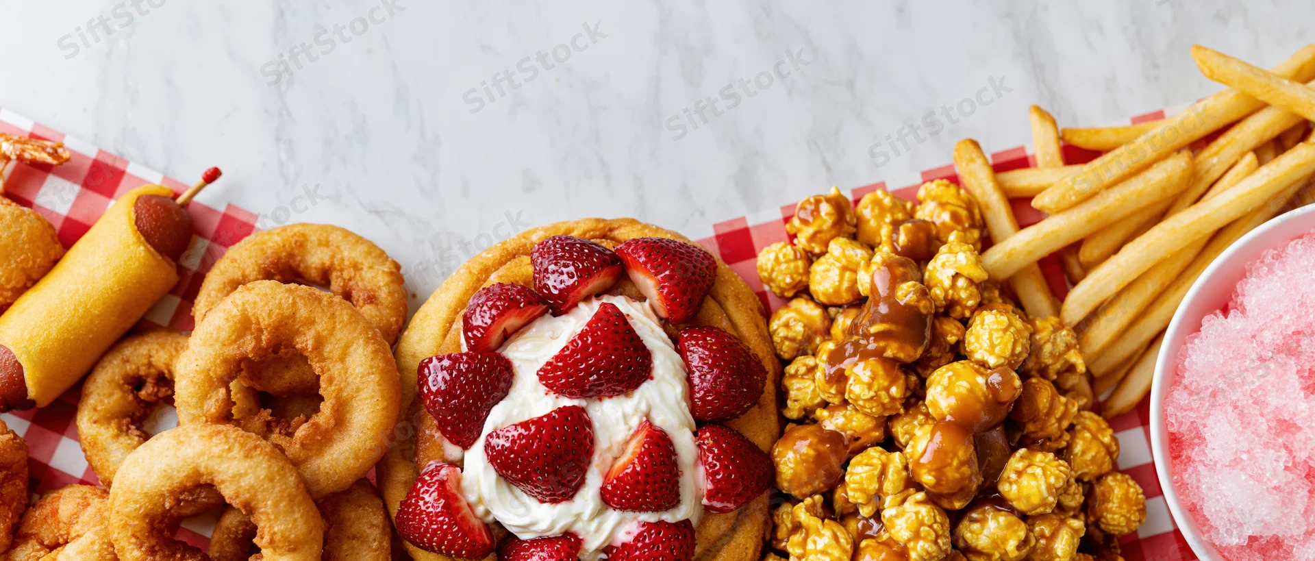 Classic american fair food arranged in a border on a marble table with checkered paper