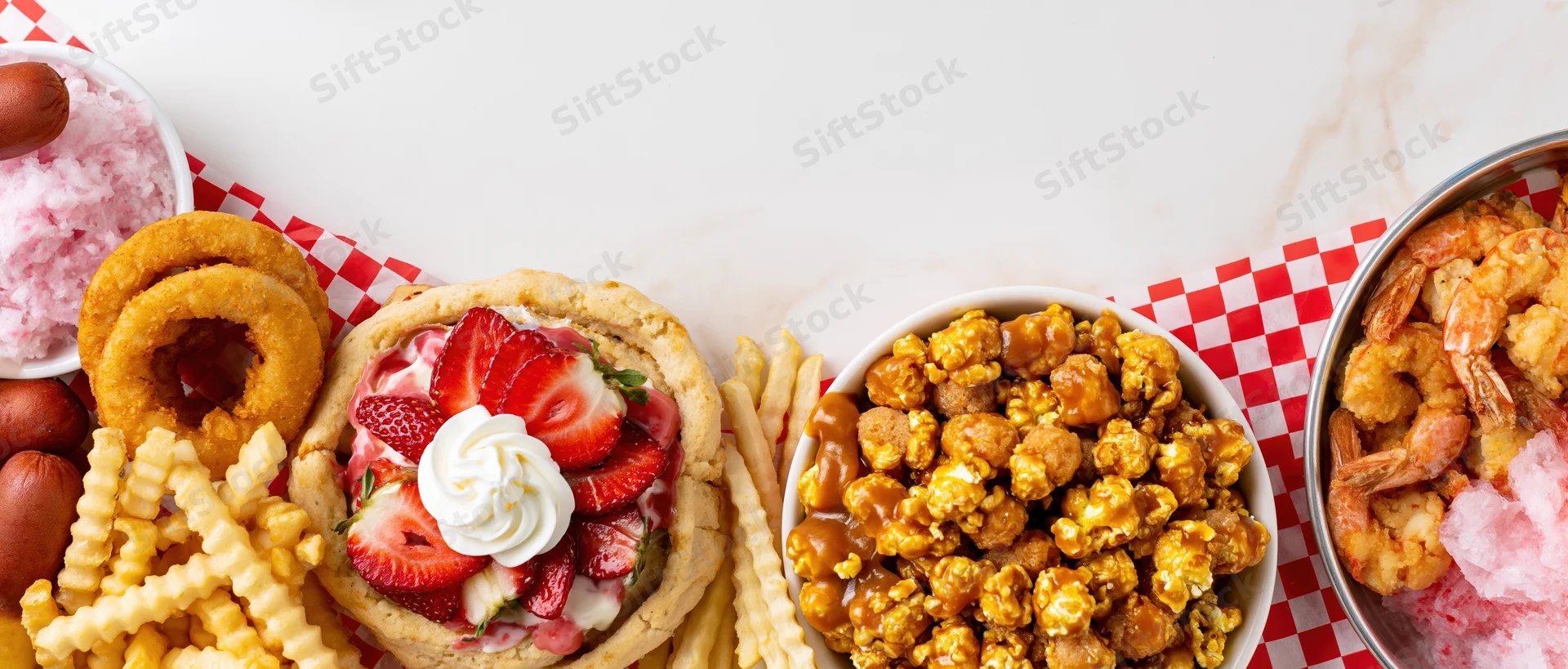 Overhead flat lay of classic american fair foods arranged in a border on a checkered tablecloth
