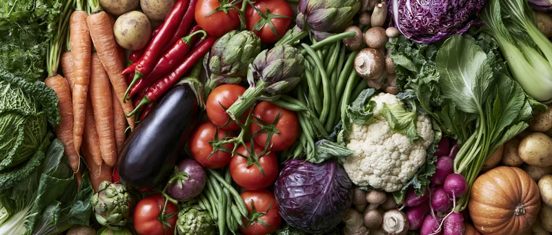 Overhead flat lay of fresh raw vegetables densely arranged in a colorful composition