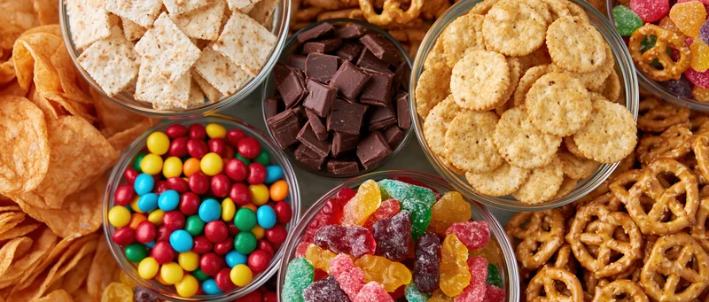 Overhead flat lay of assorted junk food snacks in glass bowls and piles