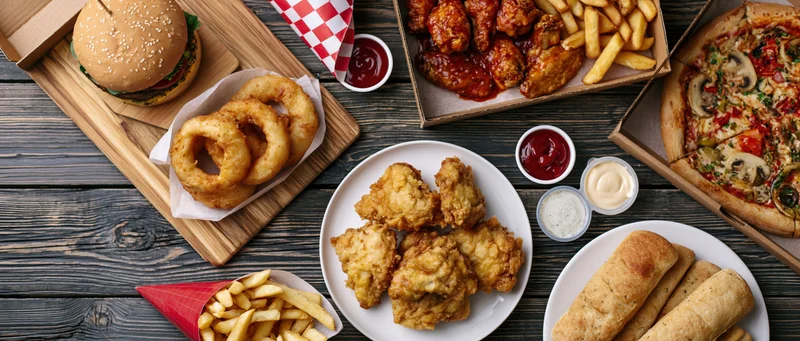 Assorted american fast food items arranged on dark wooden table in overhead flat lay view