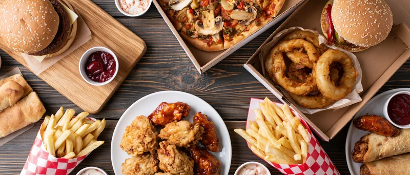 Assorted american fast food items arranged on a dark wooden table in an overhead flat lay view