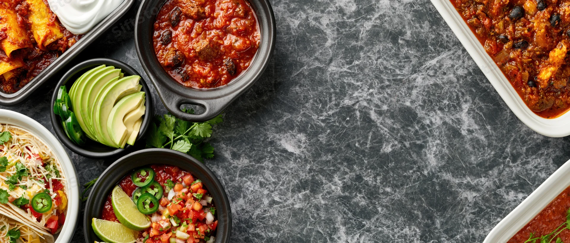 Overhead flat lay of assorted mexican dishes arranged along dark marble countertop with copyspace