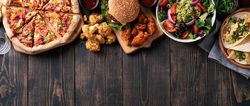 Overhead flat lay of assorted casual american restaurant food on dark wooden table