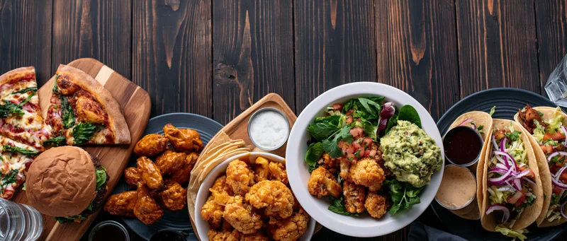 Overhead flat lay of assorted casual american restaurant food on dark wooden table