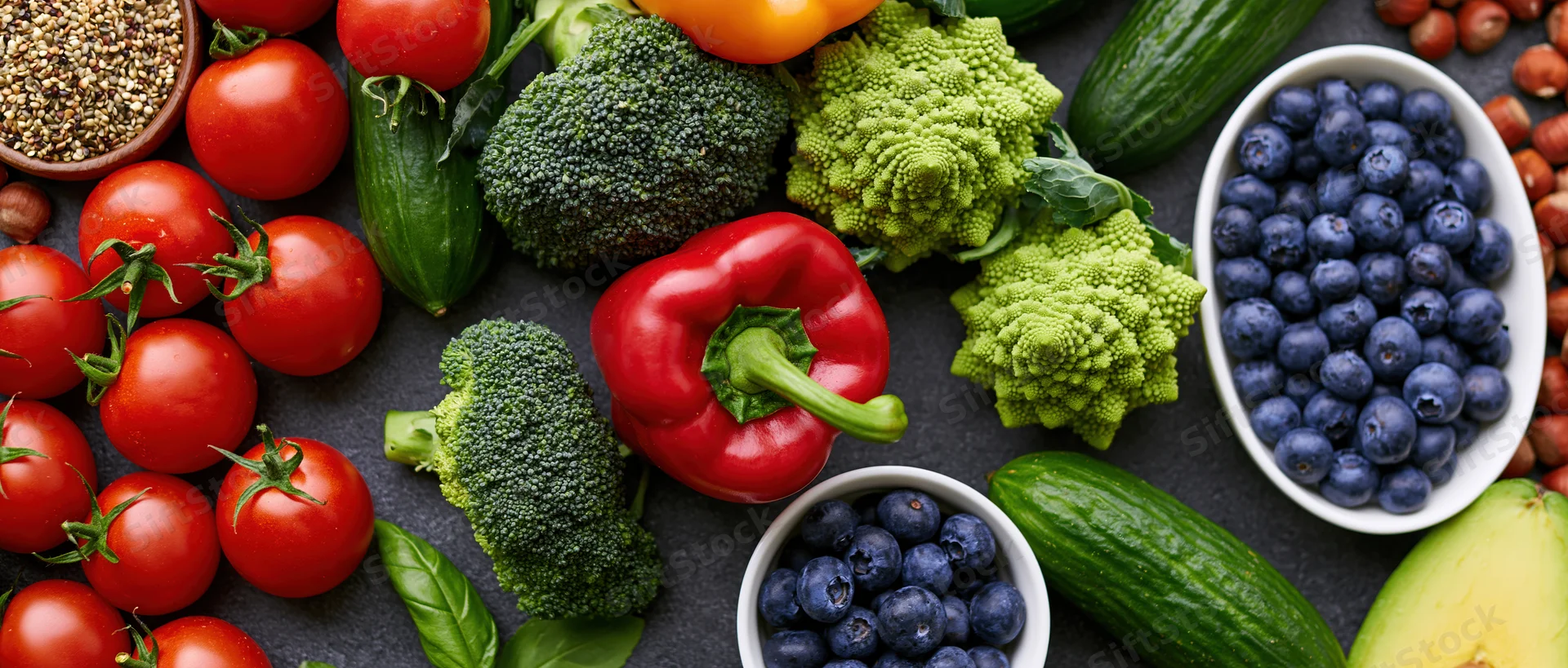Overhead flat lay of fresh vegetables fruits and nuts on dark stone surface
