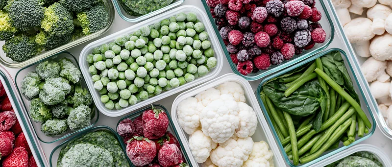 Overhead flat lay of assorted frozen vegetables and fruits in containers