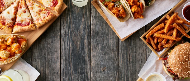 Assorted fast food items arranged on wooden table in overhead flat lay view