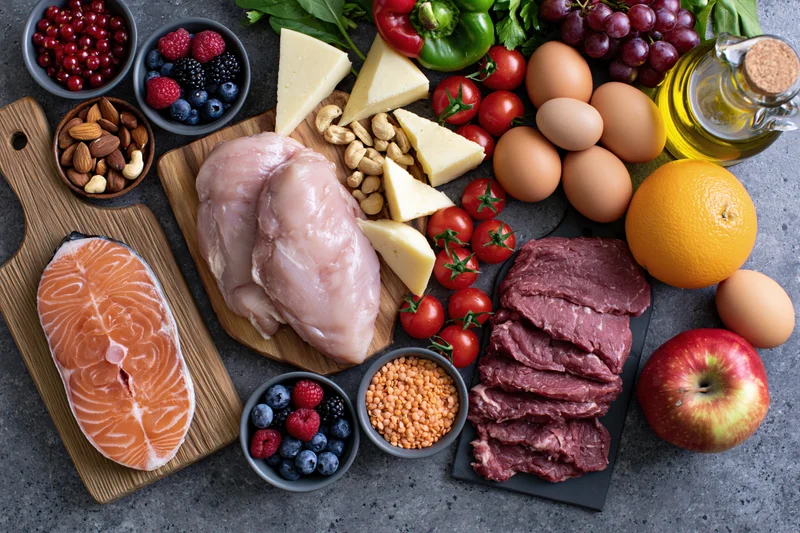 Overhead flat lay of assorted whole foods arranged on dark gray countertop