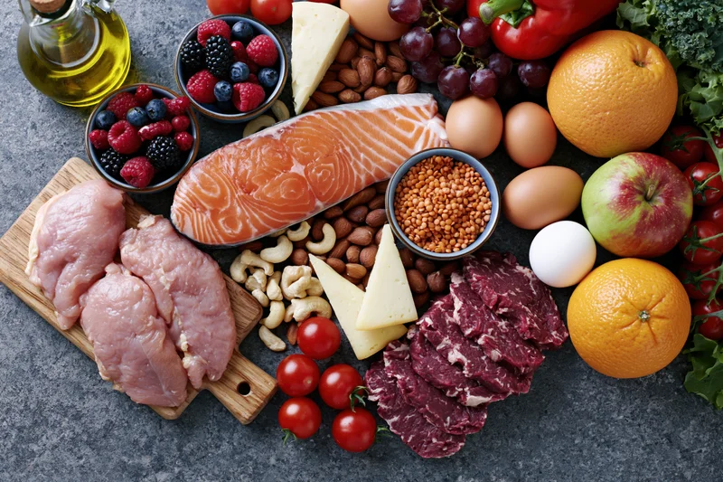 Overhead flat lay of assorted whole foods arranged on dark countertop