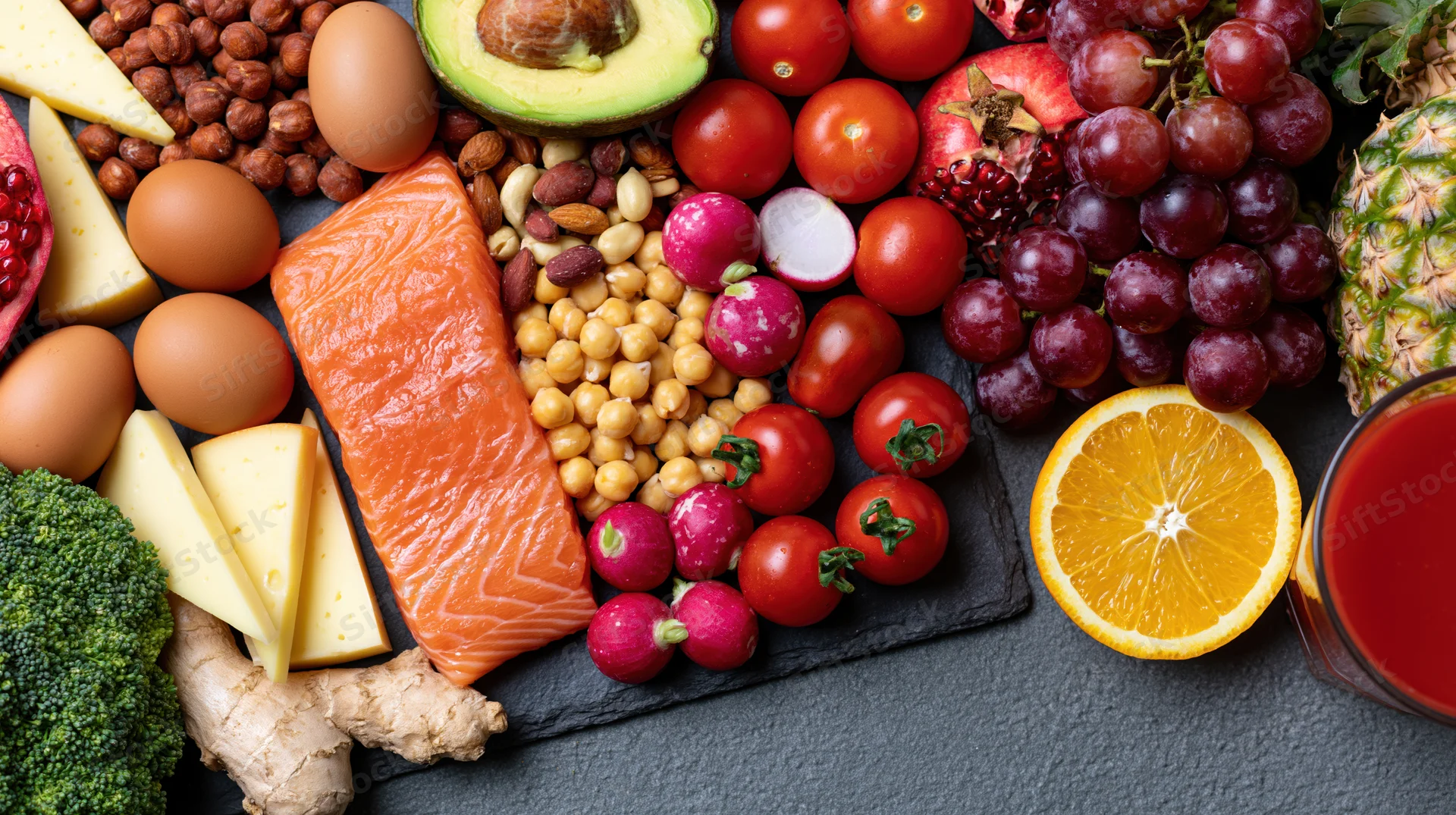 Overhead flat lay of assorted whole foods arranged on dark slate surface