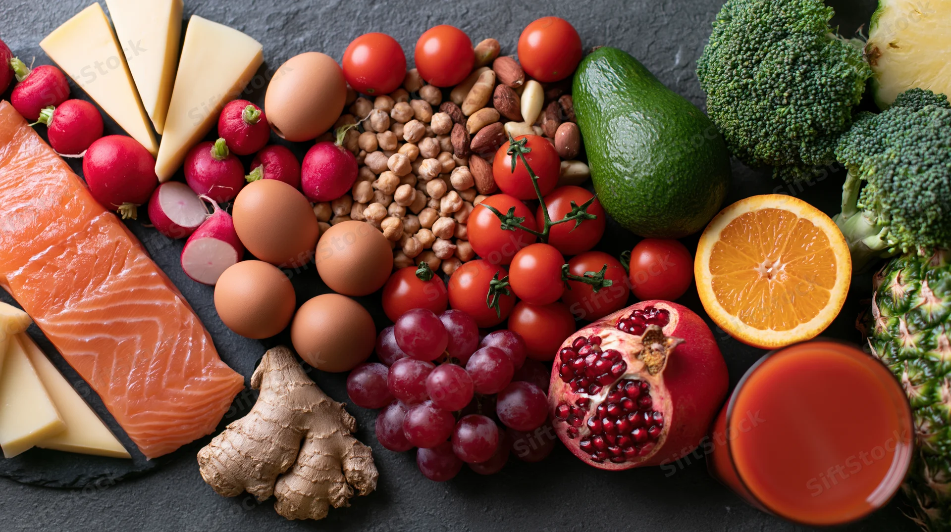 Overhead flat lay of assorted whole foods arranged on dark slate surface