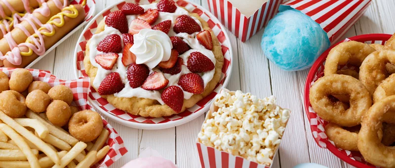 Overhead flat lay of classic american state fair foods on a wooden table