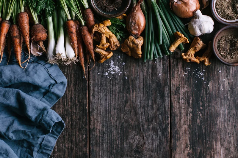 Fresh vegetables and mushrooms arranged on dark wooden table with copyspace