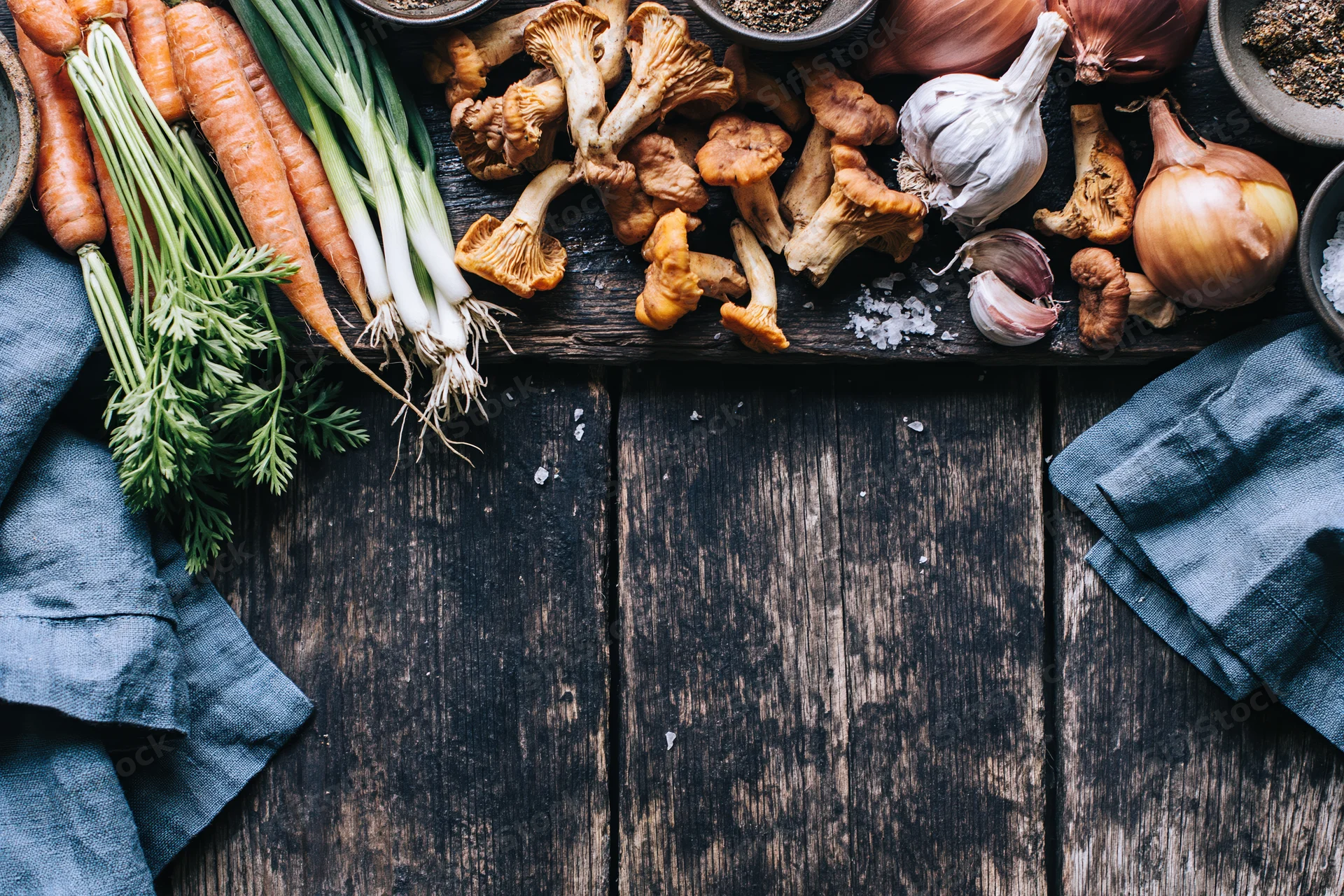 Fresh vegetables and mushrooms arranged on dark wooden table with blue cloth and copyspace below