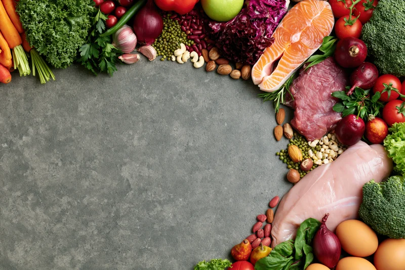 Fresh whole foods arranged in a border around a gray surface with copyspace