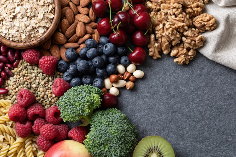 Overhead flat lay of mixed healthy foods arranged on dark surface with copyspace