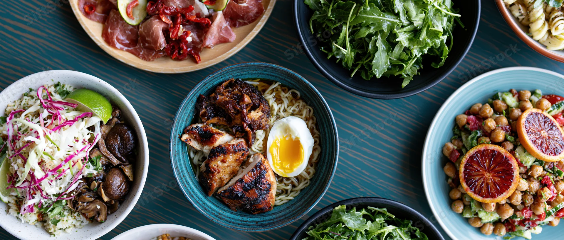 Multiple dishes arranged on a dark wooden table in an overhead flat lay view
