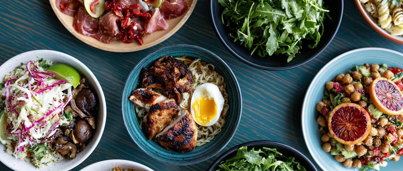 Multiple dishes arranged on a dark wooden table in an overhead flat lay view
