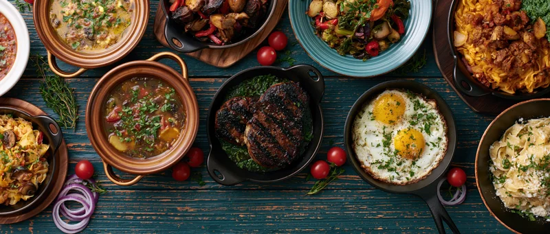 Overhead flat lay of various restaurant dishes arranged on a dark wooden table