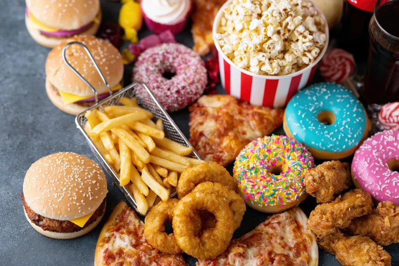 Overhead spread of assorted junk food arranged on dark surface