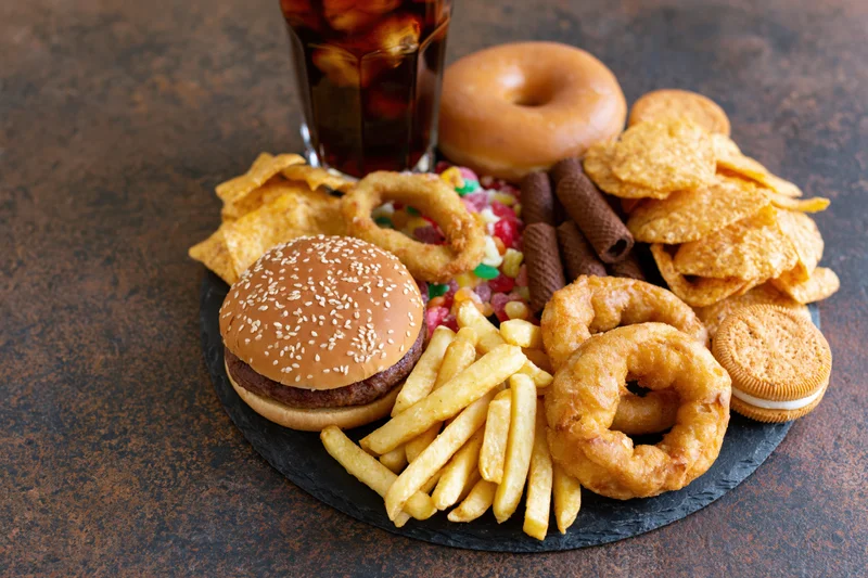 Overhead spread of junk food arranged on a dark slate board