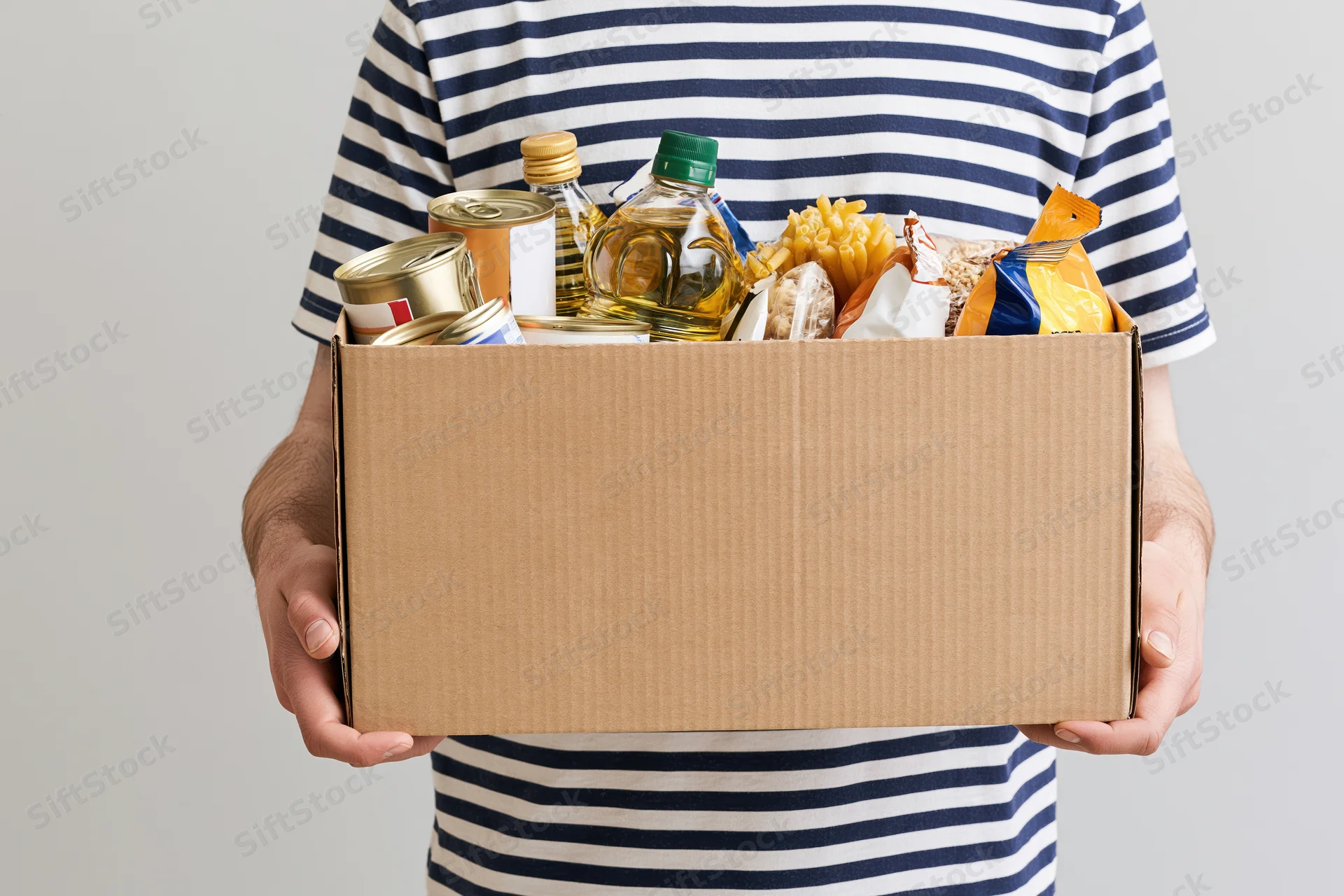 Man holding a cardboard box filled with canned goods and packaged food for donation