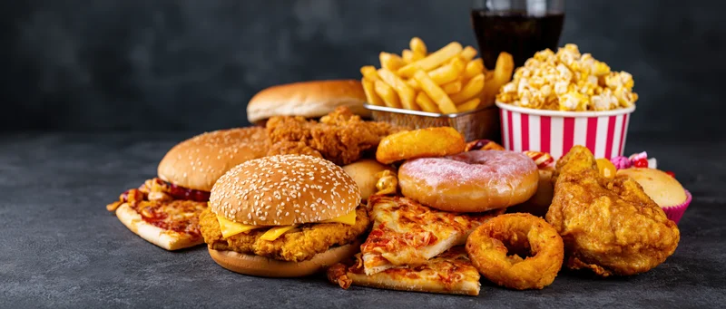 Pile of assorted junk food arranged on dark textured surface