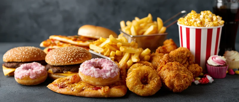 Pile of assorted junk food arranged on dark textured surface