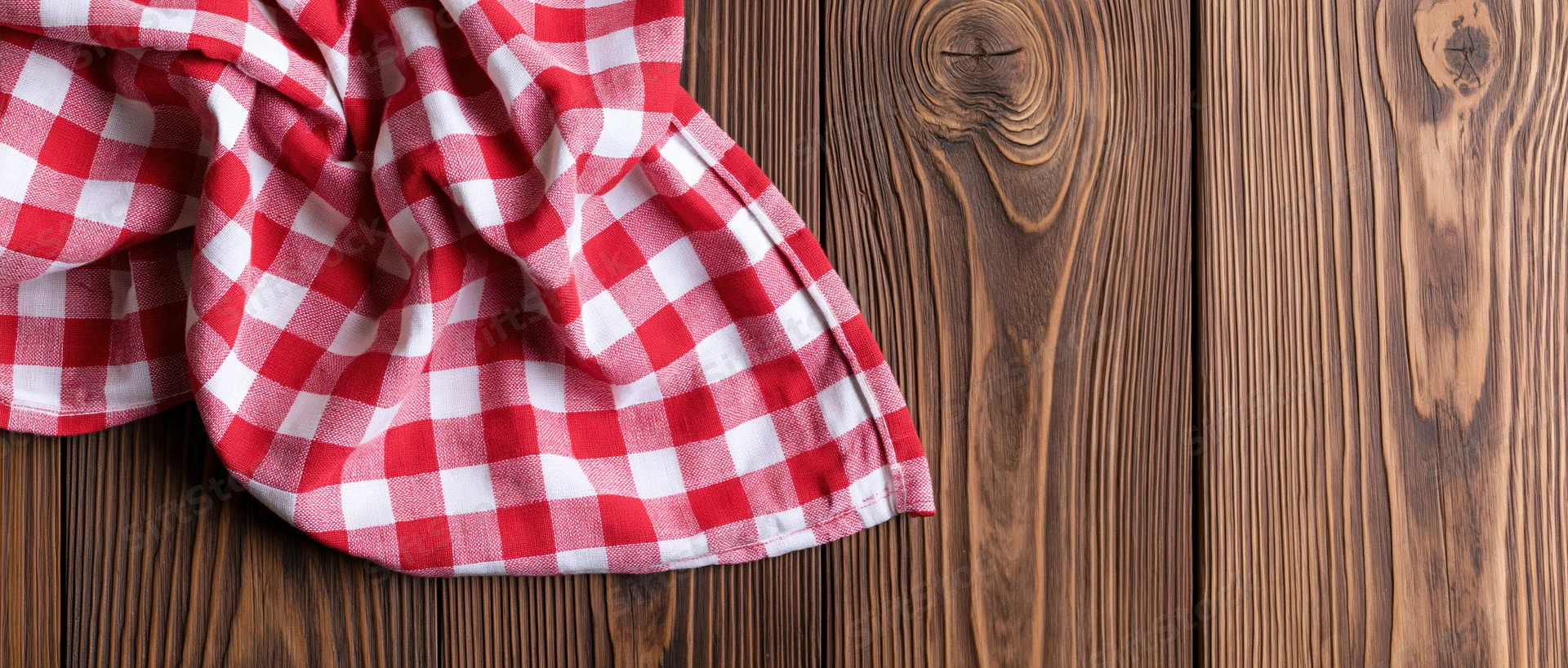 Red and white gingham napkin draped casually on wooden surface