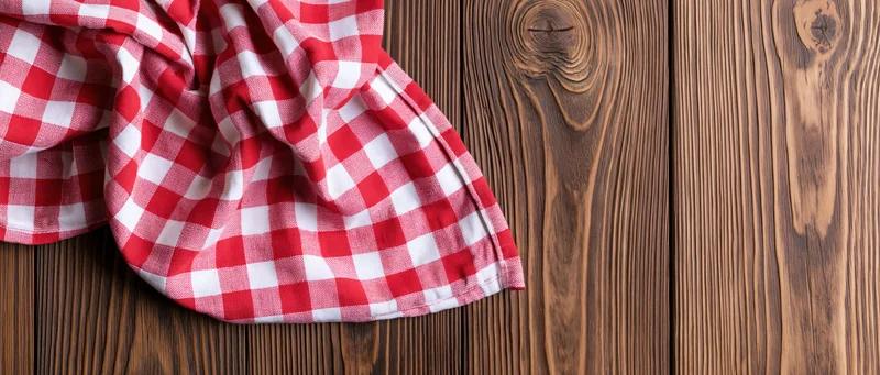 Red and white gingham napkin draped casually on wooden surface