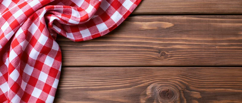 Red and white gingham cloth napkin draped on wooden table surface