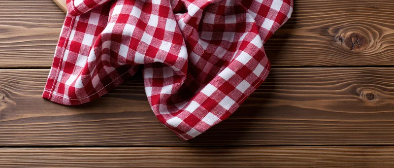 Red and white gingham napkin draped casually on wooden table surface