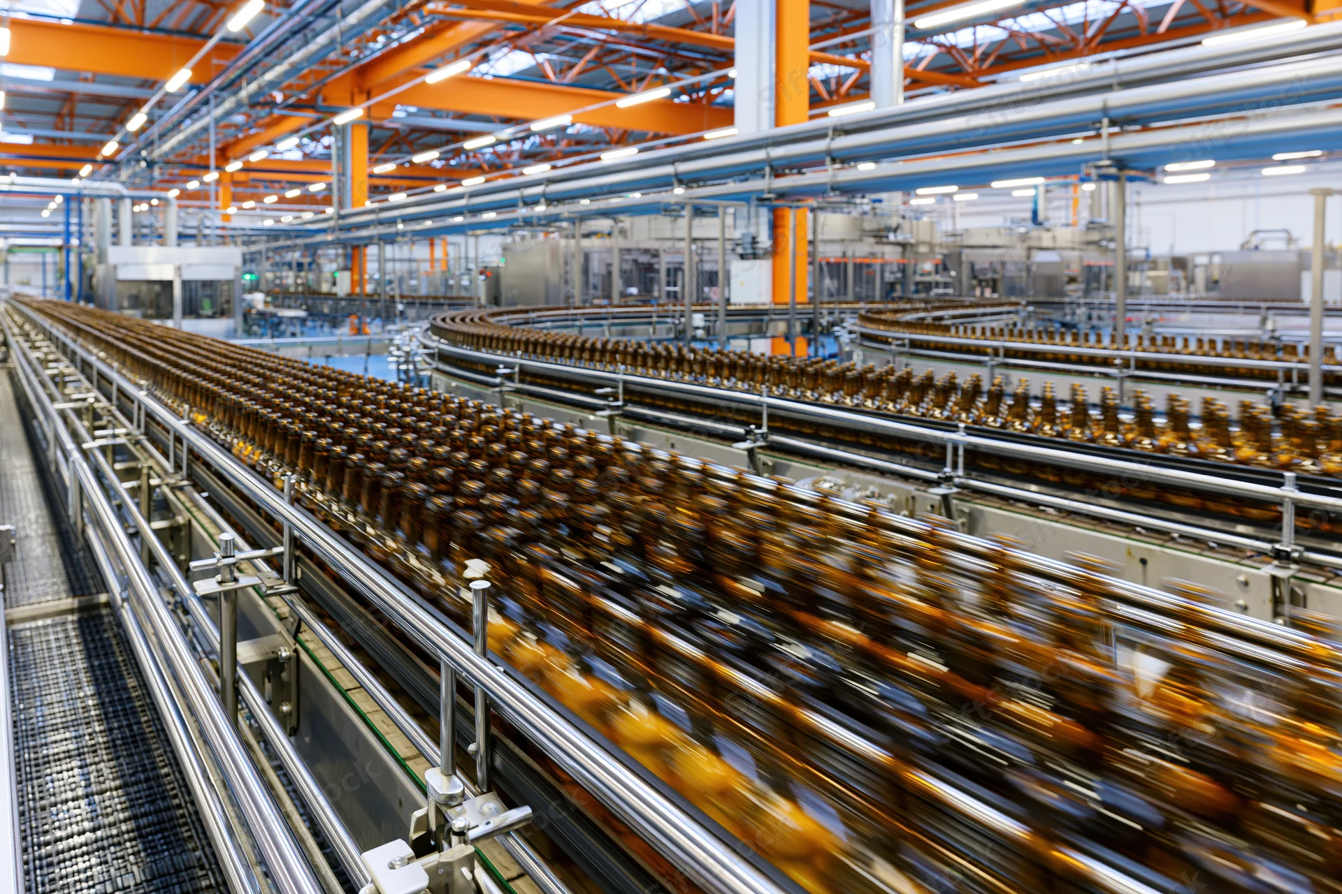 Amber glass bottles moving along converging conveyor lines in a factory