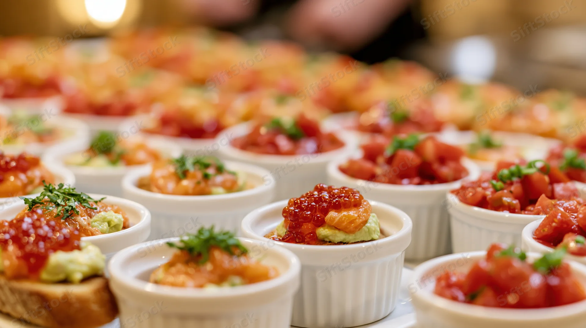 Rows of small white ramekins filled with colorful appetizers arranged on a table for a party event