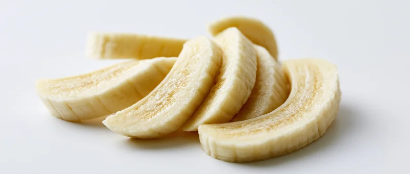 Banana slices arranged on a white surface with soft shadows
