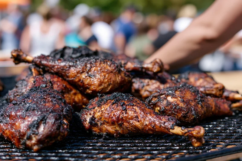 Grilled turkey legs piled on a grill tray at an outdoor event