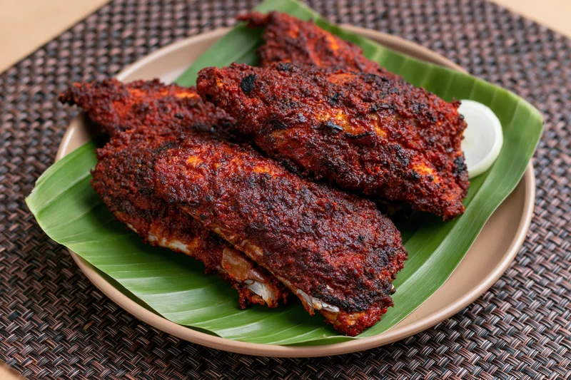 Deep-fried spiced fish pieces on a banana leaf served on a plate