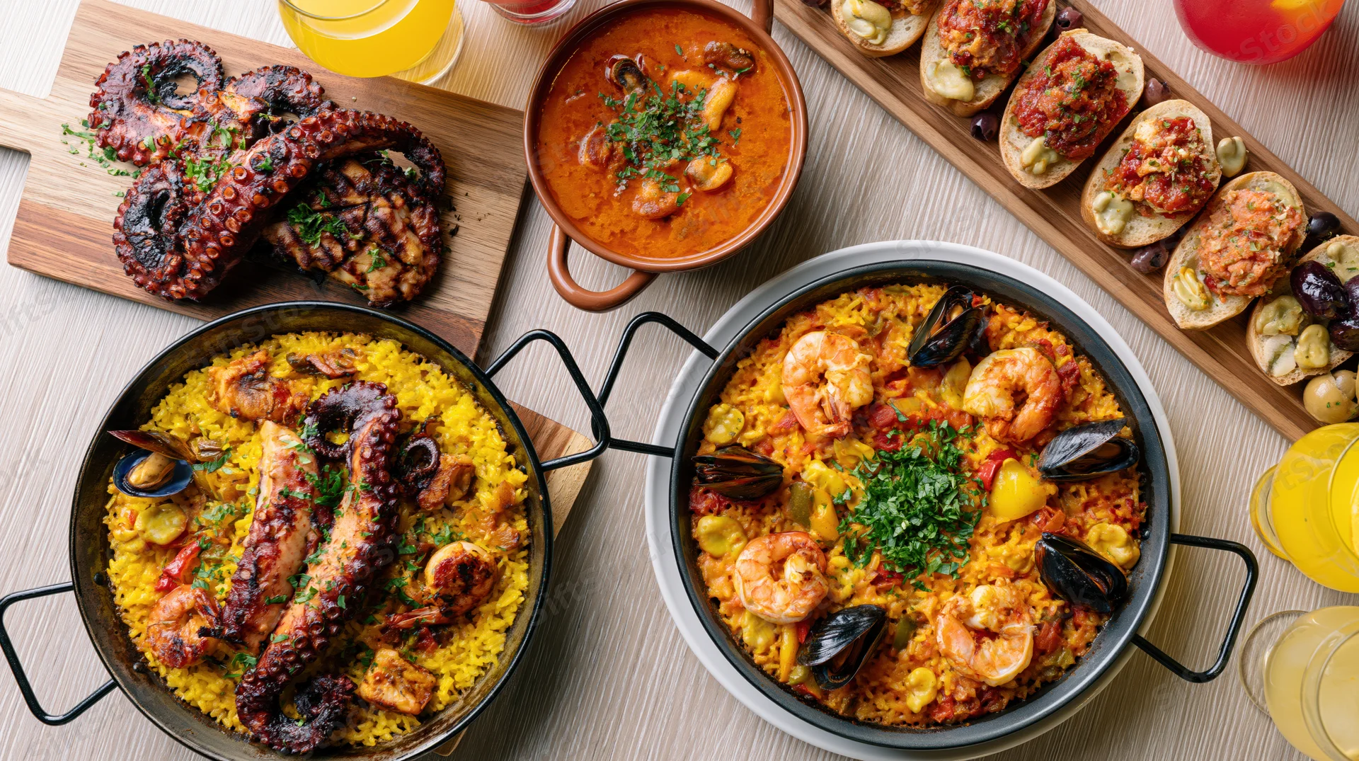 Spanish seafood feast with paella, grilled octopus, and tapas arranged on a wooden table